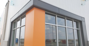 Corner of a commercial warehouse with orange wall and black metal siding around the windows