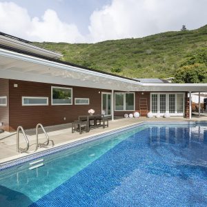 Pool with residential home with metal panel siding