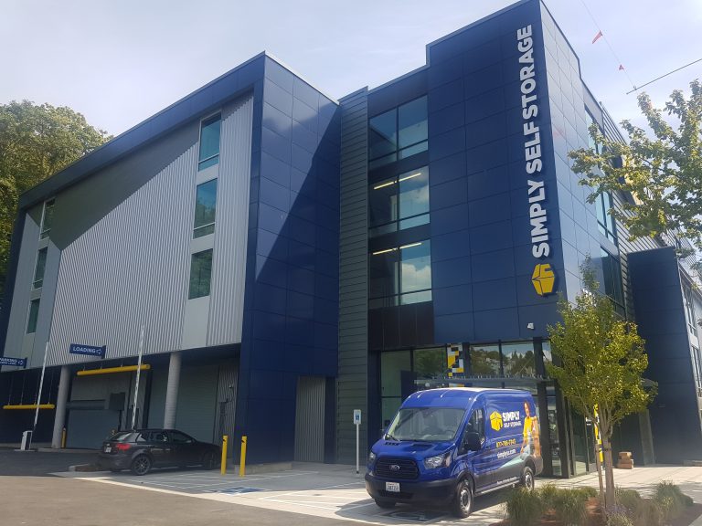3 story building with navy blue metal cladding with a van in front of the building
